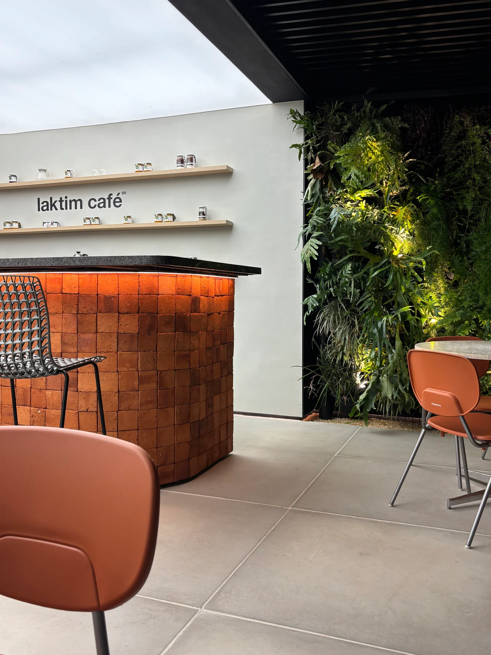 Balcão de tijolos do Laktim Café, jardim vertical e cadeiras terracota